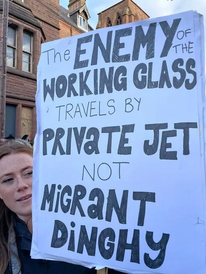 Woman holds sign on Liverpool street which says 

