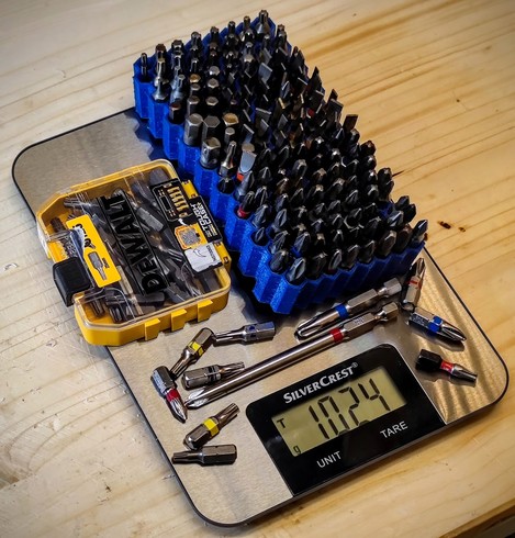 a houshold scale on a wooden plank. on the scale several hexagon bits. the scale reads 1024g.